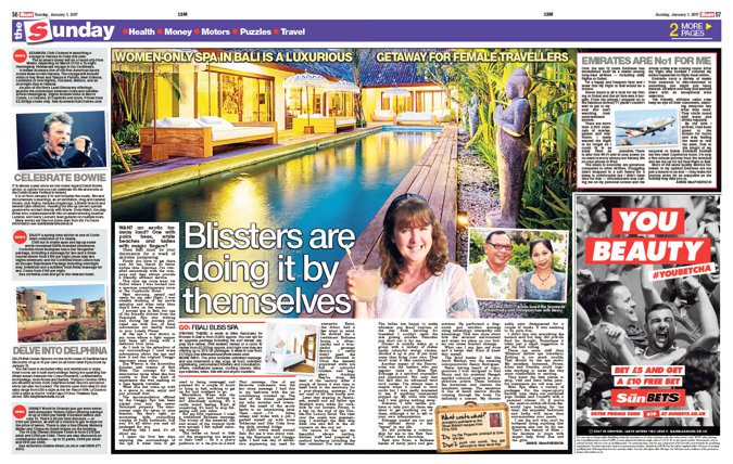 newspaper clipping - woman holding cocktail next to a long rectangular pool at a luxury Bali villa during twilight